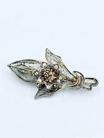 Front view of silver-tone filigree floral brooch showing flower and leaf motif