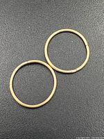 two thin gold hoops on black background