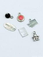 Six sterling silver charms laid out on white background