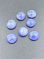 Seven round blue-violet tanzanite cabochons on black background