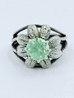 Front view shows green uranium glass stone within textured silver petal setting