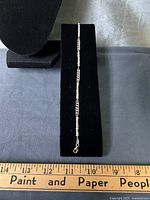 Full view of sterling bracelet on display pad next to ruler