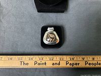 Front view of pendant showing silver frame, cabochon stone and ruler for scale