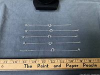 Five sterling silver horseshoe bracelets laid straight beside ruler for scale