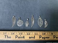 All six sterling pendants lined up with ruler for scale