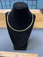 Gold-wash side of reversible omega necklace on display bust