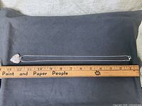 Necklace laid straight beside ruler showing overall length
