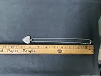 Closed heart locket and chain next to ruler showing length