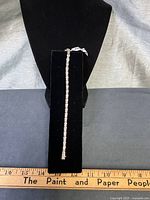 Full bracelet displayed on black velvet form beside ruler for scale