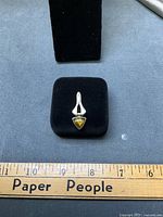 Front view of sterling silver pendant with yellow triangular amber on black display beside ruler