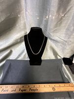 Full view of chain necklace on display bust with ruler for scale