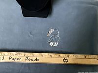 Earrings on display pad beside ruler showing full length