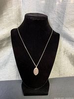 Full view of necklace on display bust showing pendant and chain drop