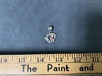 Front view of sterling silver pendant next to ruler for scale