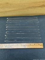 All ten sterling chains laid flat beside ruler