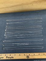 All ten sterling chains laid flat beside ruler