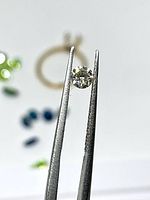 Diamond held in tweezers, showing size and color