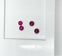 Four round cabochon rubies on white background