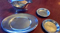 Overview of gravy boat, underplate and two dishes on table