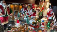 Wide view of cabinet with large Santas, nutcracker, rocking horse ornaments and small trees