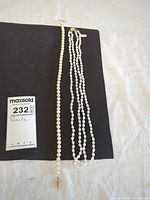 Two pearl necklaces side by side on black board