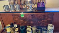 Group shot of entire lot on cabinet showing pewter, ceramic, glass pieces