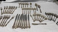 Full lot laid out showing forks, knives, multiple types of spoons and butter spreader