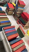 Stacks and bin of assorted vintage cloth-bound hardcovers in various colours
