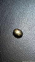 Top view of oval cabochon black star sapphire showing golden asterism