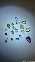 Group of mixed loose gemstones on white background showing variety of colors and cuts