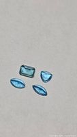 Four loose blue topaz stones on neutral background