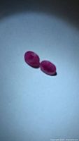 Pair of oval rubies under spotlight