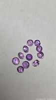 Group of 11 round purple amethyst gemstones on neutral background