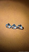 Three pale blue faceted aquamarine stones displayed on brown surface