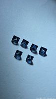 Six square-cut blue sapphires arranged on flat surface