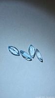 Four marquise-cut sky blue topaz gems on neutral background