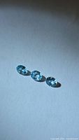 Three blue zircon gemstones arranged side by side on neutral background
