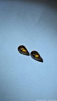 Pair of pear-shaped champagne orange zircons on flat surface