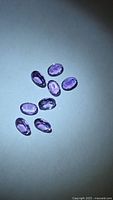 Eight oval purple amethysts on neutral background