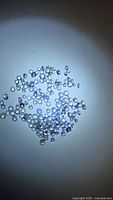 Pile of small round tanzanite stones under flashlight