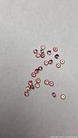 Loose round pink-orange sapphires scattered on grey background
