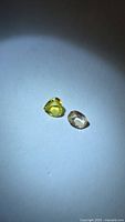 Pair of chrysoberyl gemstones on neutral background under spotlight