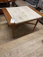 Three-quarter view of table showing travertine top, wood rails, tapered legs