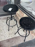 Two black round-seat metal stools on patio