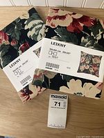 Front view of two sealed IKEA LEIKNY floral cushion covers showing labels and pattern