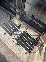 Top view of the two black metal and wood slat folding chairs on terrazzo floor