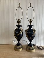 Pair of black urn-form lamps with gold roses shown full view on table