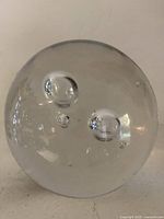 Front view of clear glass paperweight showing internal bubbles