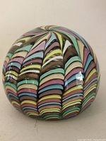 Front angled view showing overall multicolor ribbon design on glass sphere