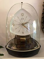 Full view of clock under glass dome on base